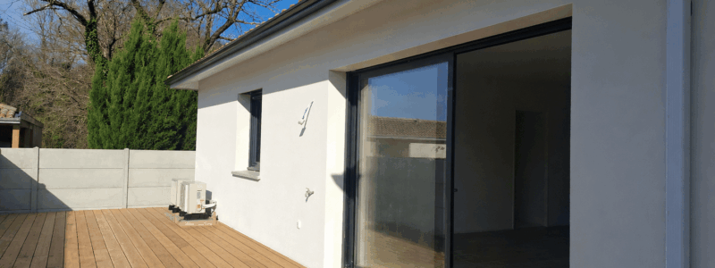 Terrasse en bois moderne devant une grande baie vitrée et façade blanche d'une maison contemporaine.